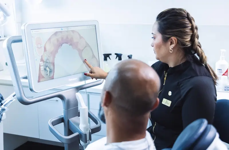 Paciente acompanhando o escaneamento 3D do próprio sorriso na tela, ao lado da equipe da IEM